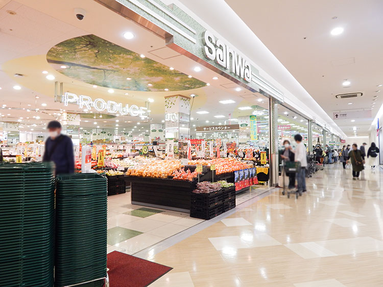 スーパー三和 サクラス戸塚店の売り場風景。新鮮な野菜や果物、肉や魚が整然と並んでいる。棚やカートにはさまざまな食品が豊富に揃っており、広々とした店内に明るい照明が当たっている。