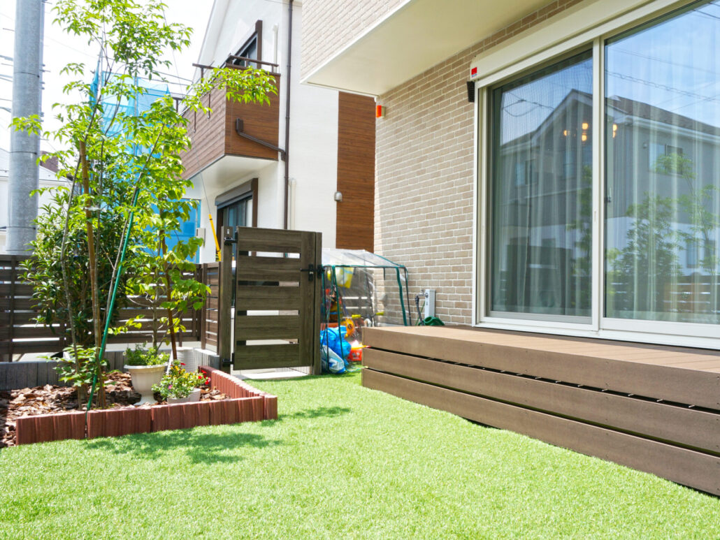 人工芝にウッドデッキのある、ナチュラル煉瓦スタイルの落ち着いた印象の戸建て住宅