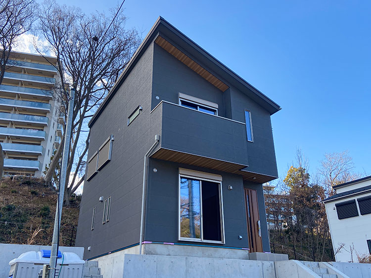 ダークグレーの外壁にグレーと木目調デザインが映えるスタイリッシュな新築戸建て住宅外観の写真